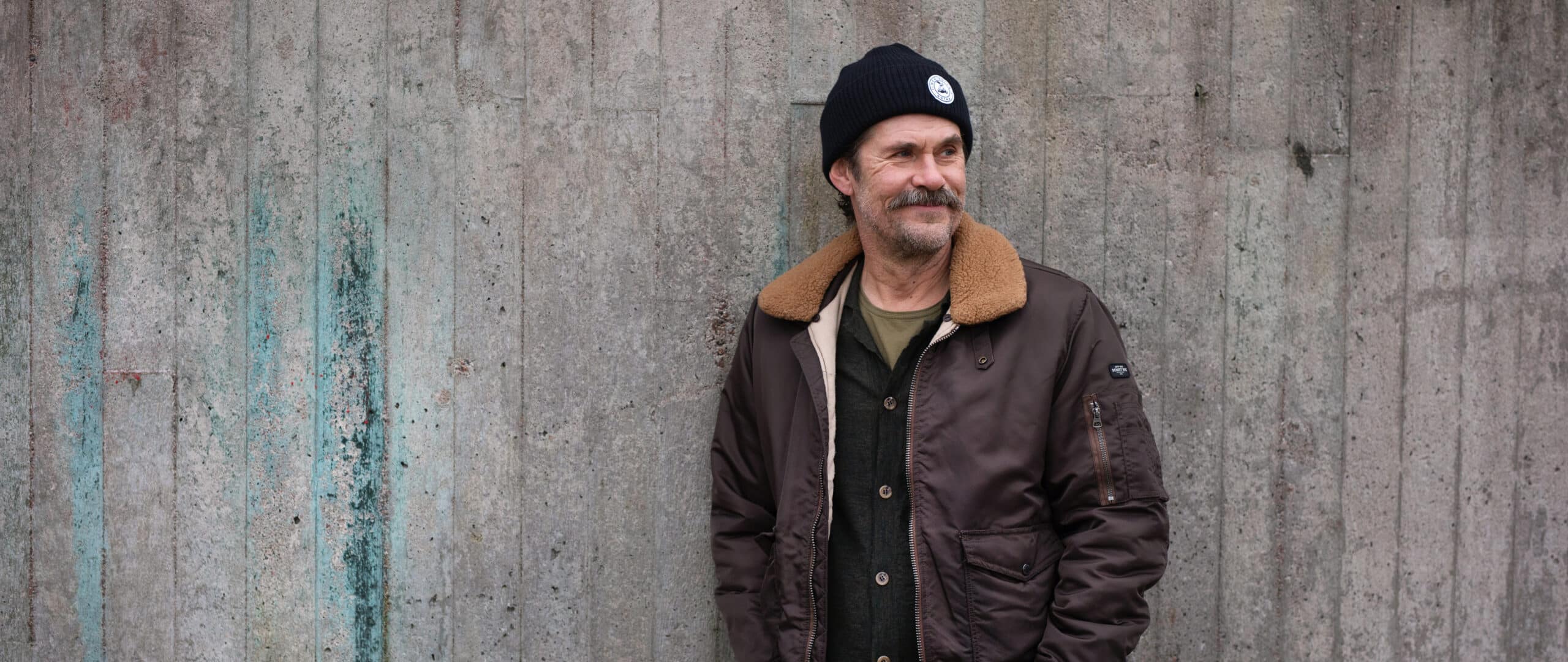 Tommi Korpela nojaa betoniseinään.